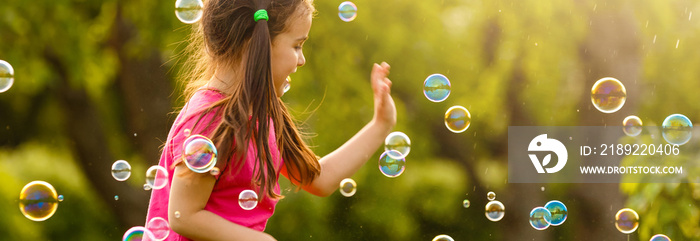 Curly girl catch a soap bubbles. Happy childhood concept.