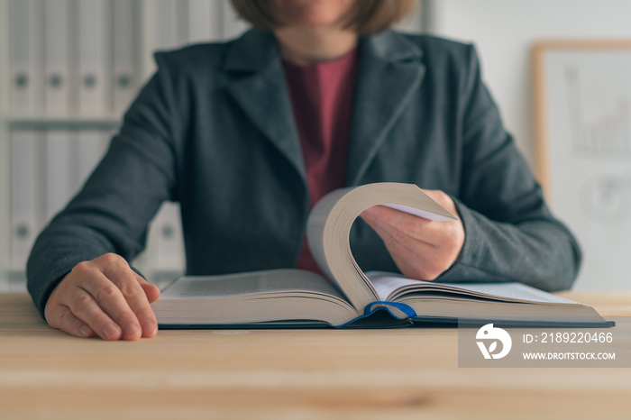 Businesswoman reading book at office desk