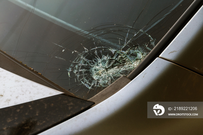 汽车挡风玻璃碎了。车轮下的石头在肮脏的道路上迅速砸碎了汽车玻璃。Crim