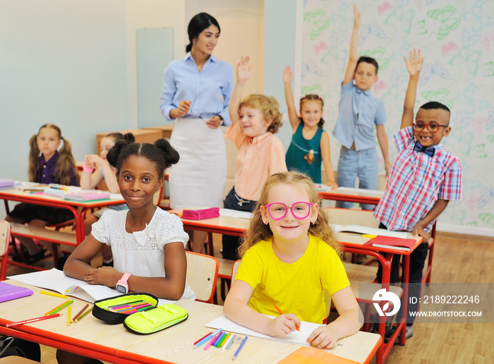 小孩子学校的孩子们微笑着举起手来回应