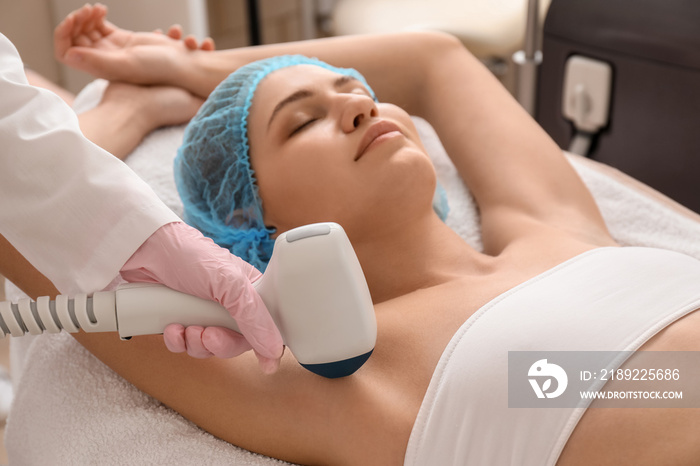 Beautiful woman undergoing procedure of laser hair removing in beauty salon