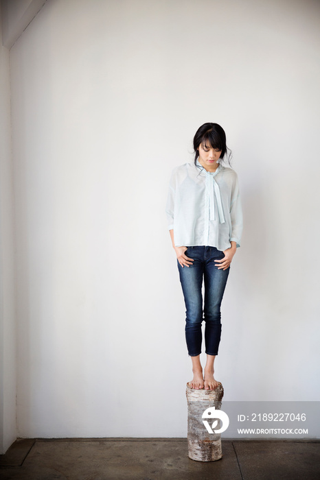 Woman standing on birch snag in empty room