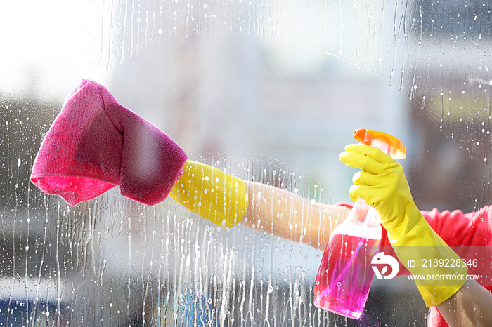 戴着橡胶手套的女人用海绵和洗涤剂清洁窗户，特写