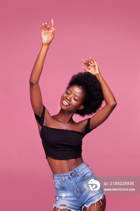 举起双手跳舞，一个非洲发型的漂亮年轻非裔美国女孩穿着黑色衣服摆出姿势