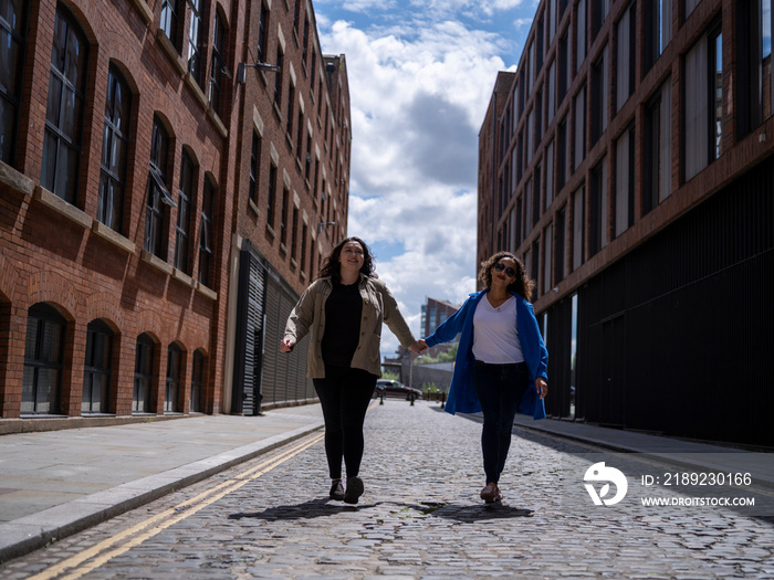 UK, Happy lesbian couple walking on street