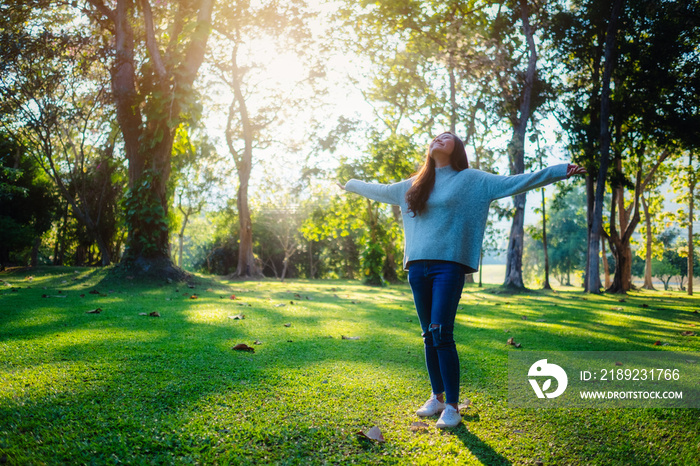 Portrait image of a beautiful asian woman standing and opening arms among nature in the park before 