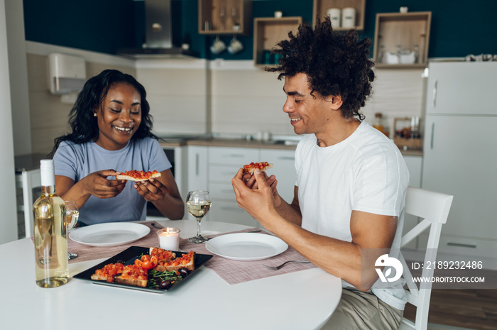 African american couple drinking white wine and having dinner at home