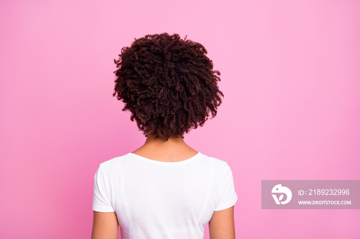 Rare view of curly woman wearing white casual t-shirt isolated on pastel pink color background