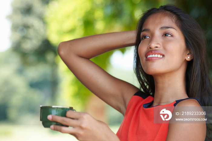 Portrait of young woman holding coffee cup with hand in hair