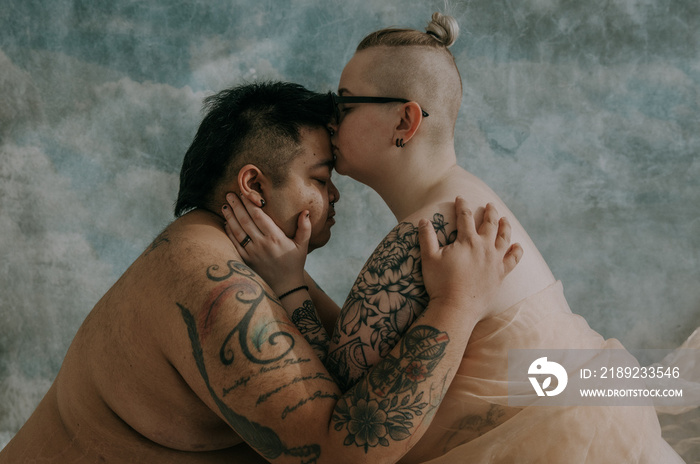 1 non-binary person kissing the forehead of non-binary asian person