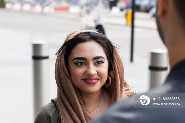 Young man and woman in street, face to face, smiling