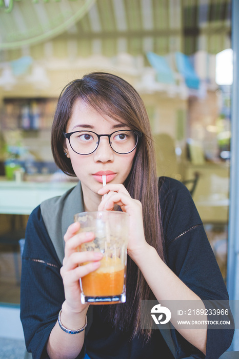 年轻女子在人行道咖啡馆喝奶昔