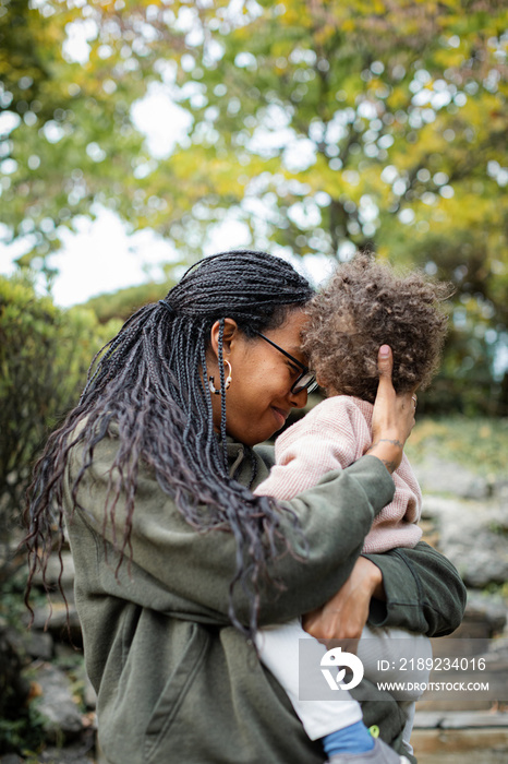 Black mother hugging toddler boy and smiling in fall