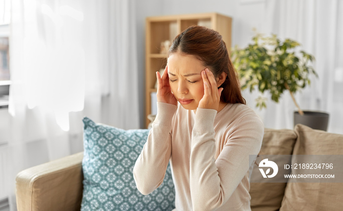 people and health concept - sick asian woman having headache at home