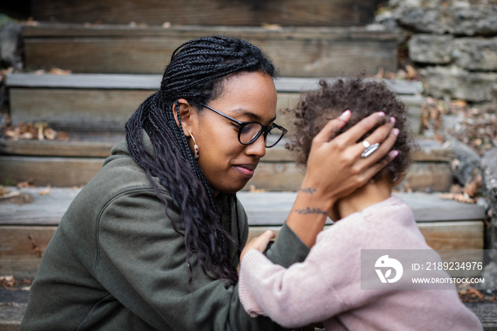 Black mother holding sons head and smiling in fall