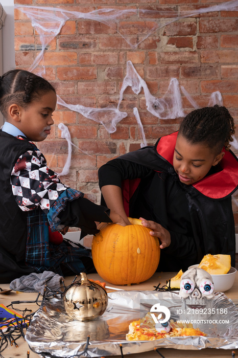 Children in Halloween costumes making Jack OLantern