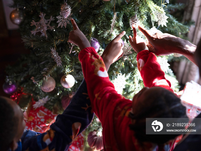 Father with sons hanging ornaments on Christmas tree