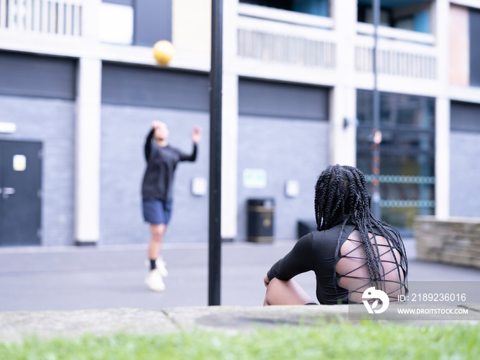 Two female friends playing basketball outdoors