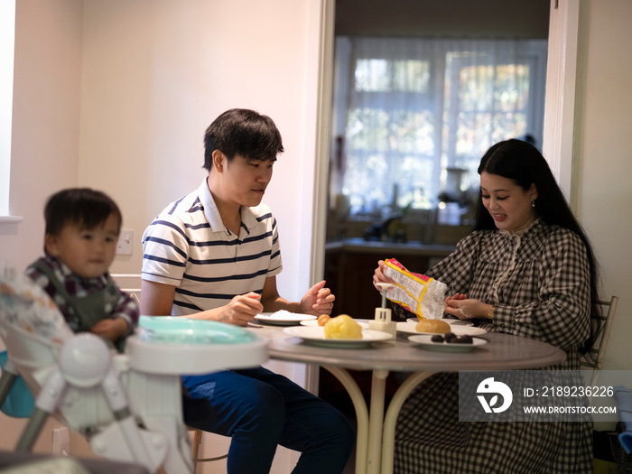 Parents with baby son preparing food at home