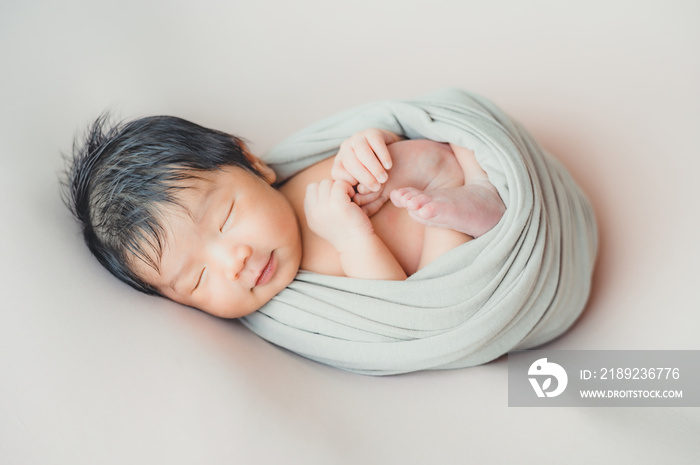 Asian newborn baby wrapprd in cocoon sleeping