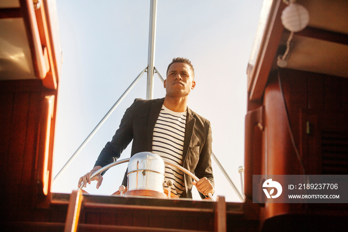 Young man steering yacht