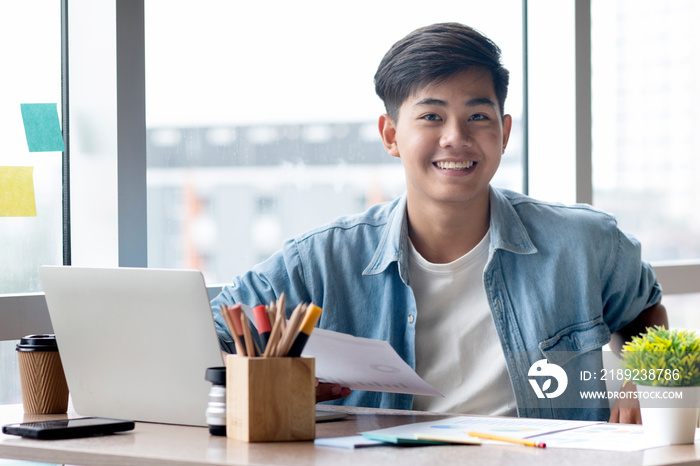 Young businessman in casual clothes sitting at his desk in the office.