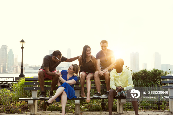 Friends talking on bench city in background