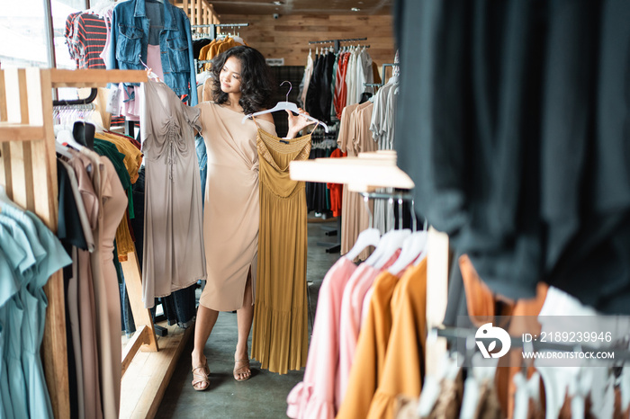 亚洲美女在时装店看衣服。购物理念