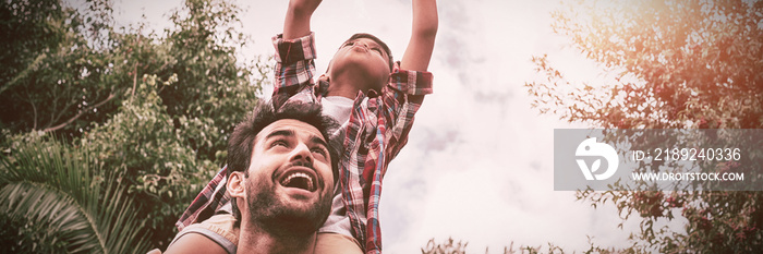 Low angle view of father carrying son playing with airplane