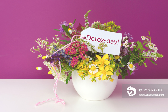 Schild mit der Aufschrift Detox-day in einem Strauss Heil- und Teekräuter