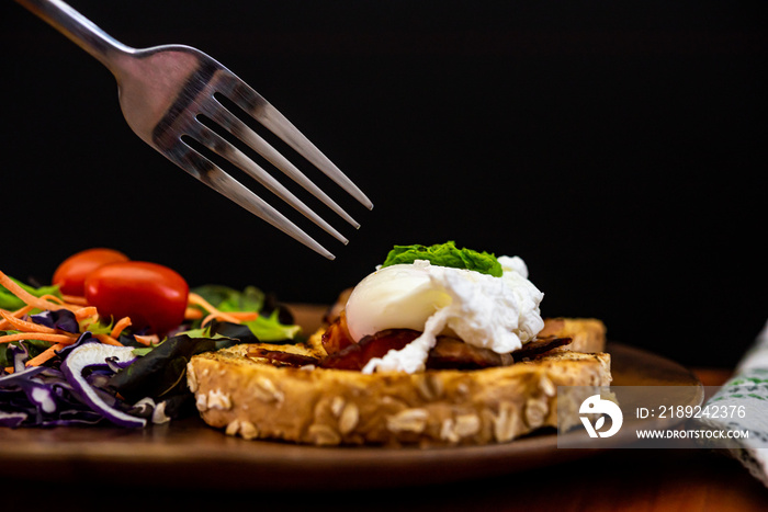 自制餐，有机本尼迪克特鸡蛋配新鲜沙拉和叉子，放在木板上即食，有益健康