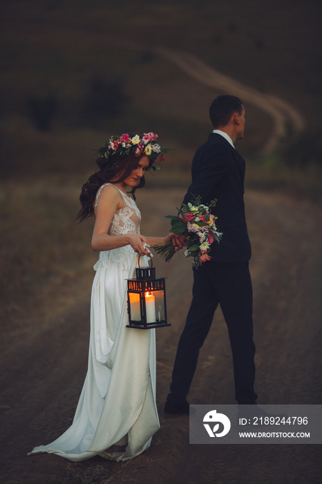 Portrait of the bride and groom with a lantern in the countryside on the road.