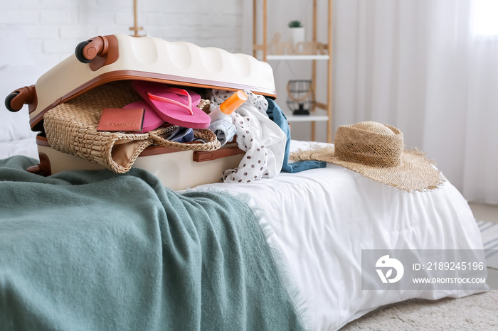 Packed suitcase with belongings on bed. Travel concept