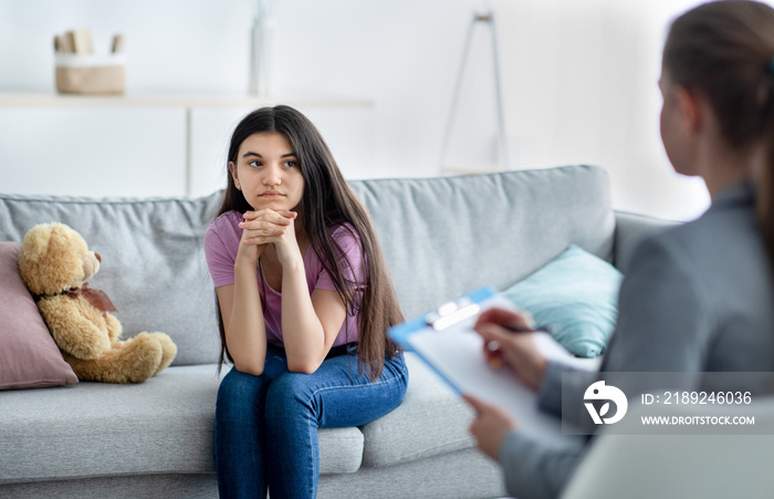 Female psychologist consulting depressed Indian teenage girl at office