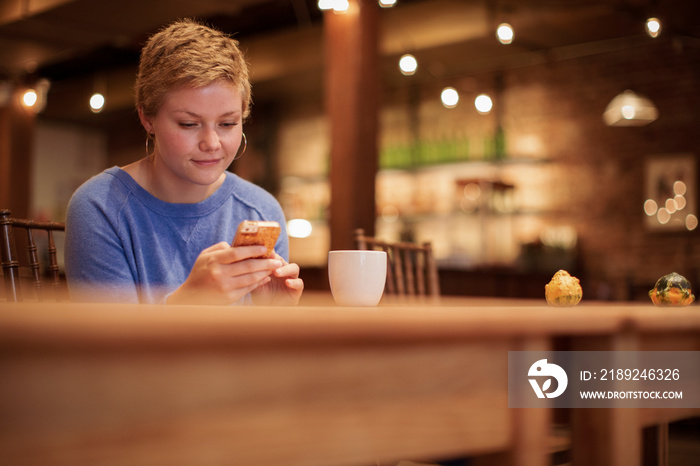 Low angle view of businesswoman with short hair using smart phone while sitting in coffee shop