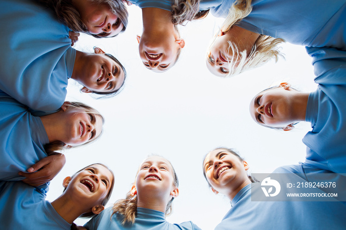 Low angle view of happy girls team huddling against clear sky