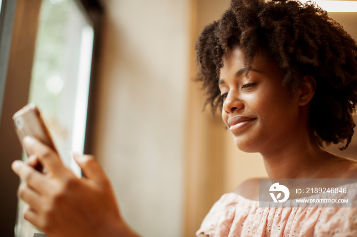 Low angle view of smiling businesswoman with curly hair using smart phone while sitting in office ca