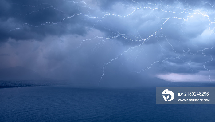 Calm tropical blue sea under amazing storm clouds with lightning