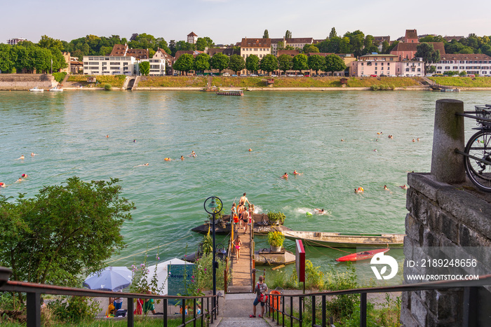 View of people with swimming suit go down to small pier from riverside to float on Rhine river durin