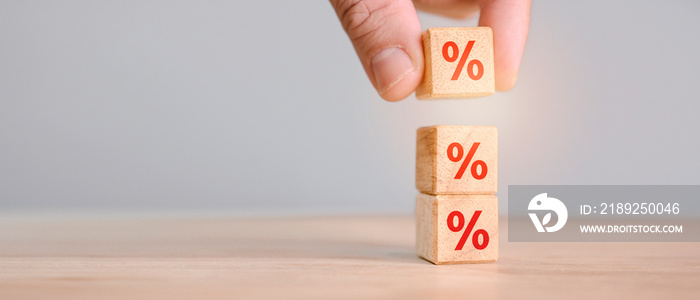 Interest rate financial and mortgage rates concept. Hand putting wood cube block increasing on top w