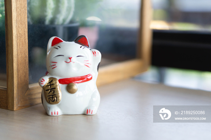 Maneki neko幸运猫展示手头的文字，意思是丰富的木桌背景，选择焦点