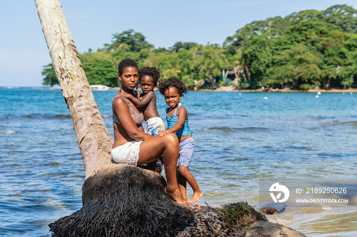 Imagen de una hermosa familia afro americana sobre una palmera viendo a cámara disfrutando de un día