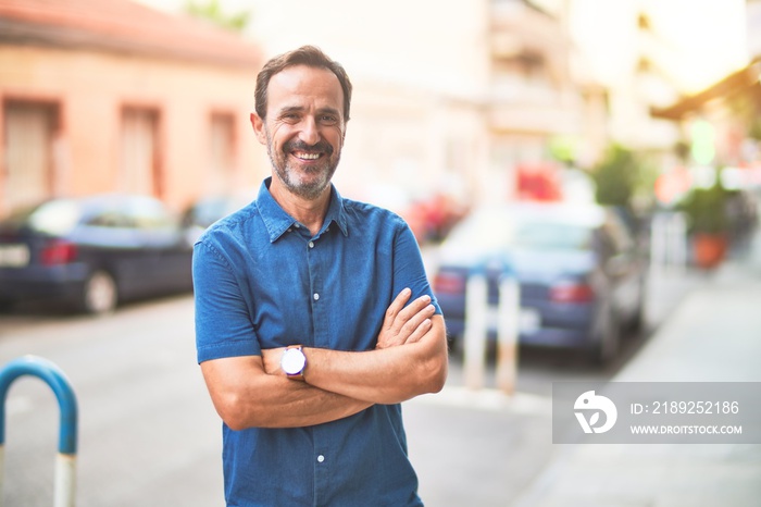 Middle age handsome man standing on the street smiling