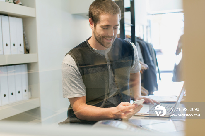 Clerk with cell phone and laptop at work