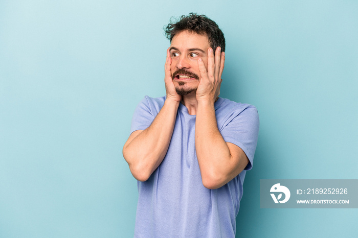 Young caucasian man isolated on blue background scared and afraid.