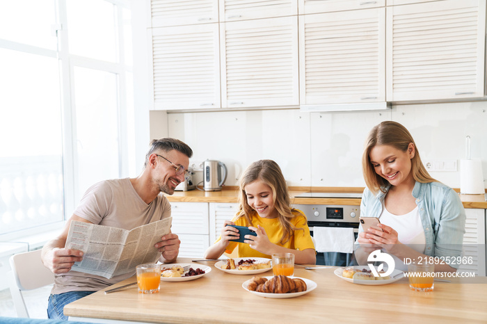 Photo of family using smartphones while having breakfast