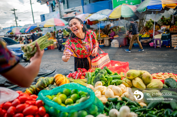 Retrato de Una Mujer feliz comprando espárragos frescos en un mercado local.