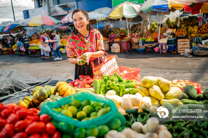 Mujer indígena guatemalteca comprando vegetales frescos en un mercado local.