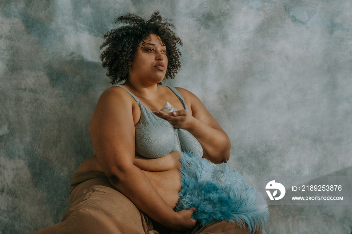 portrait of a plus size non-binary person holding feathers and seashell