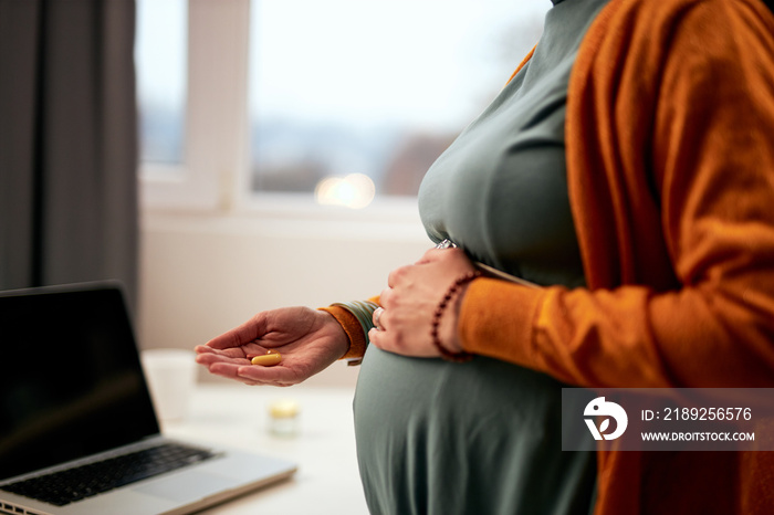 Cutout picture of pregnant caucasian businesswoman standing in office, touching belly and holding pi